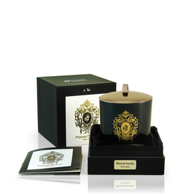 Candela Tiziana Terenzi Almond Vanilla in vaso di vetro nero con coperchio lucido e decorazione dorata. La candela è presentata in una confezione nera elegante, con il logo distintivo Tiziana Terenzi e un opuscolo informativo a lato, risaltando l’artigianato italiano dal 1968.