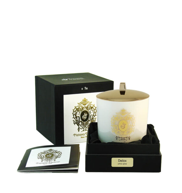 Candela Tiziana Terenzi Delox in vaso di vetro nero con coperchio lucido e decorazione dorata. La candela è presentata in una confezione nera elegante, con il logo distintivo Tiziana Terenzi e un opuscolo informativo a lato, risaltando l’artigianato italiano dal 1968.