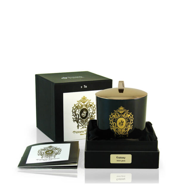 Candela Tiziana Terenzi Ecstasy in vaso di vetro nero con coperchio lucido e decorazione dorata. La candela è presentata in una confezione nera elegante, con il logo distintivo Tiziana Terenzi e un opuscolo informativo a lato, risaltando l’artigianato italiano dal 1968.