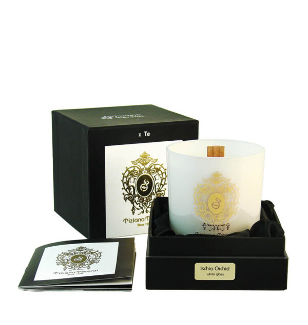 Candela Tiziana Terenzi Ischia Orchid in vaso di vetro bianco con stoppino in legno e decorazione dorata. Presentata in una confezione nera elegante con un opuscolo informativo a lato, risaltando il logo distintivo del marchio Tiziana Terenzi, noto per il suo artigianato dal 1968.