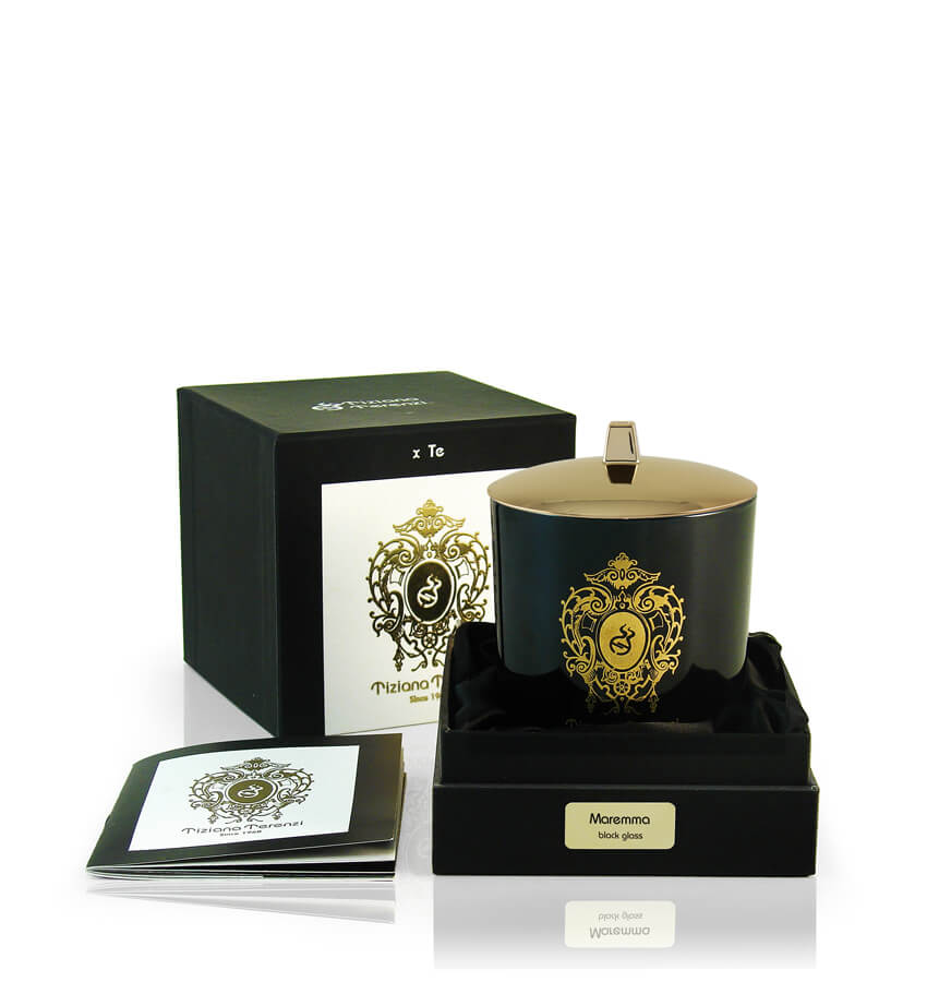 Candela Tiziana Terenzi Maremma in vaso di vetro nero con coperchio lucido e decorazione dorata. La candela è presentata in una confezione nera elegante, con il logo distintivo Tiziana Terenzi e un opuscolo informativo a lato, risaltando l’artigianato italiano dal 1968.