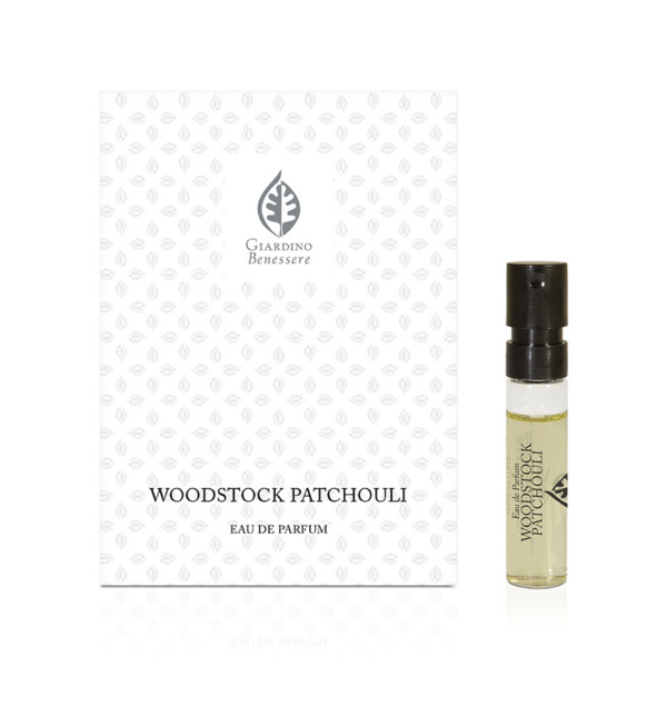 Campioncino del profumo Woodstock Patchouli di Giardino Benessere, con flacone trasparente e tappo nero accanto alla scatola decorata con un motivo a foglia e il nome del profumo stampato in nero.